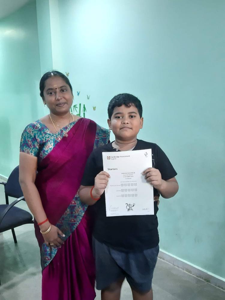 A young Thrive learner proudly holding his Cambridge English Starters certificate.